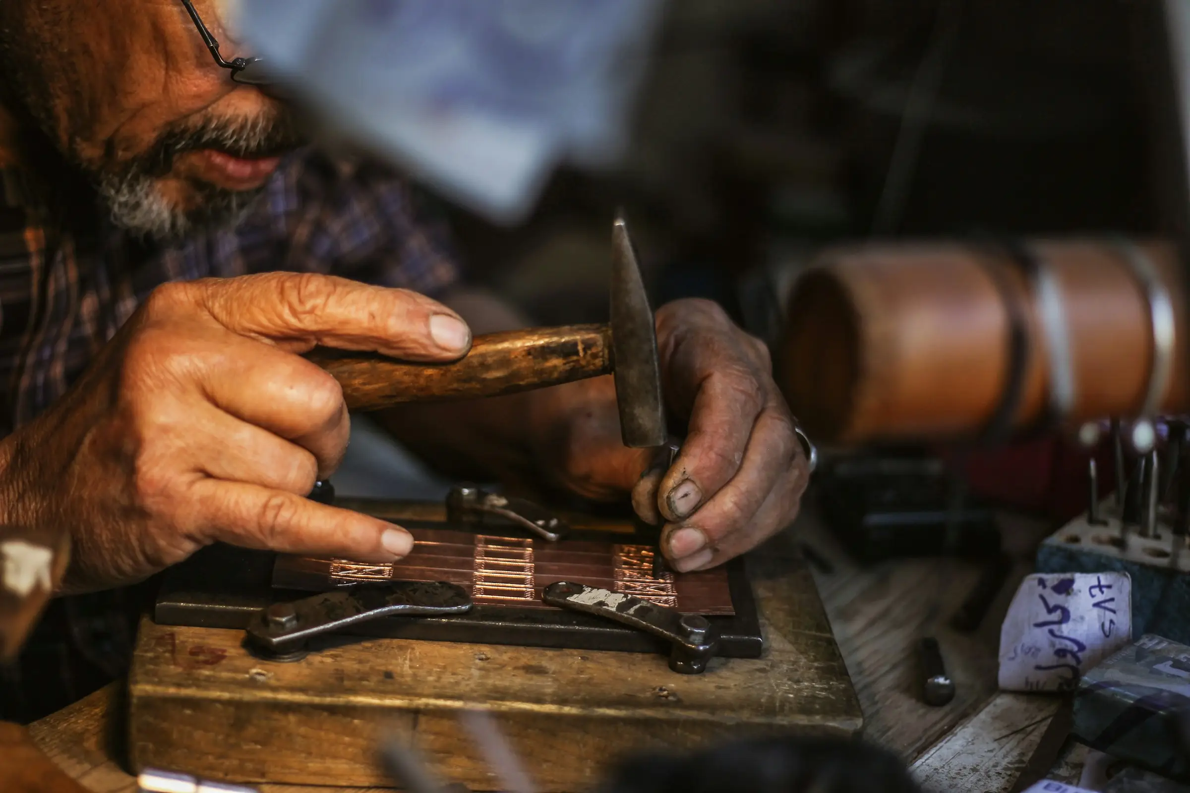 Le mani dell'orafo lavorano una placca di metallo con martello e cesello