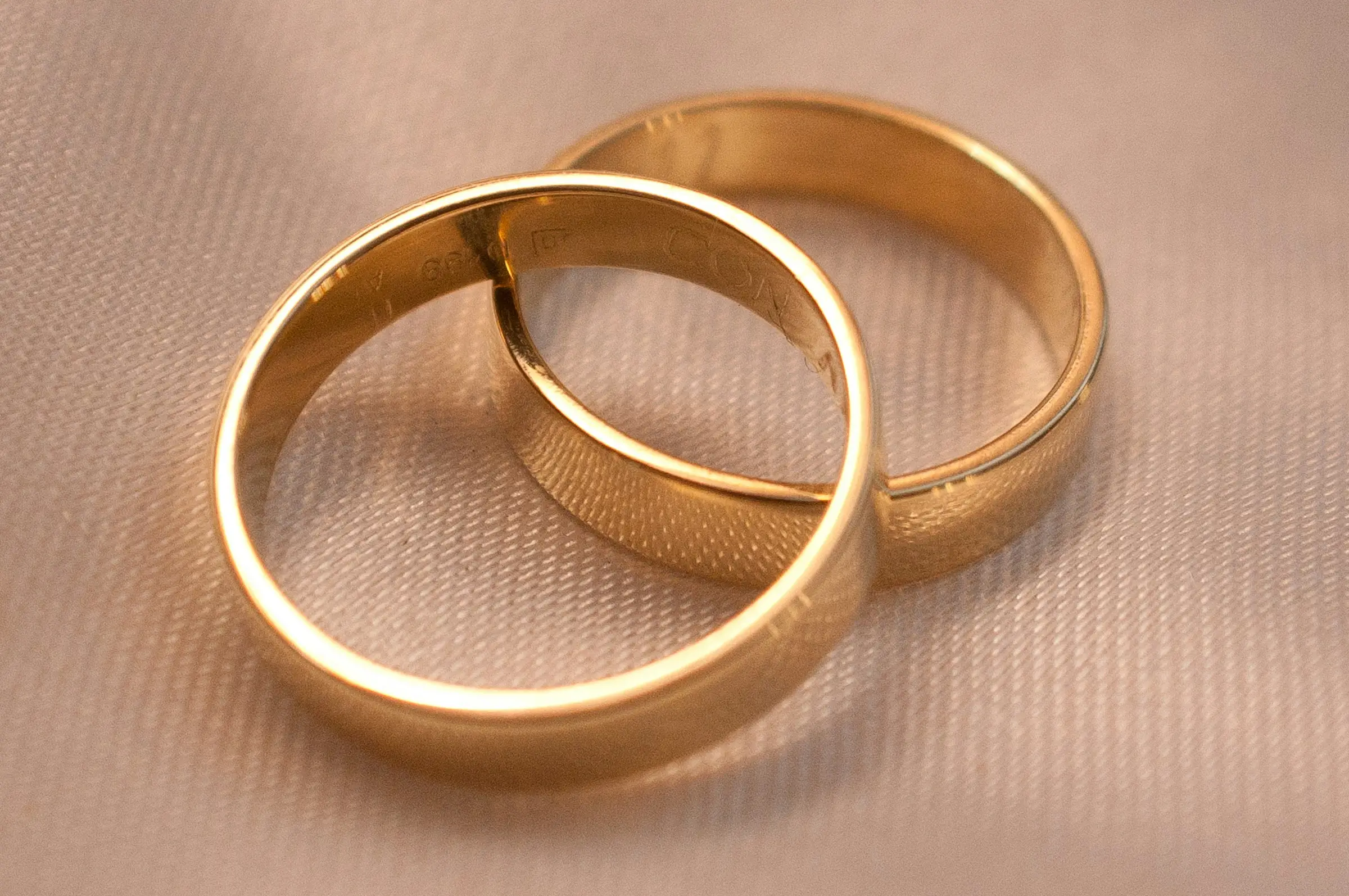 Due fedi d'oro giallo intrecciate su un tessuto chiaro