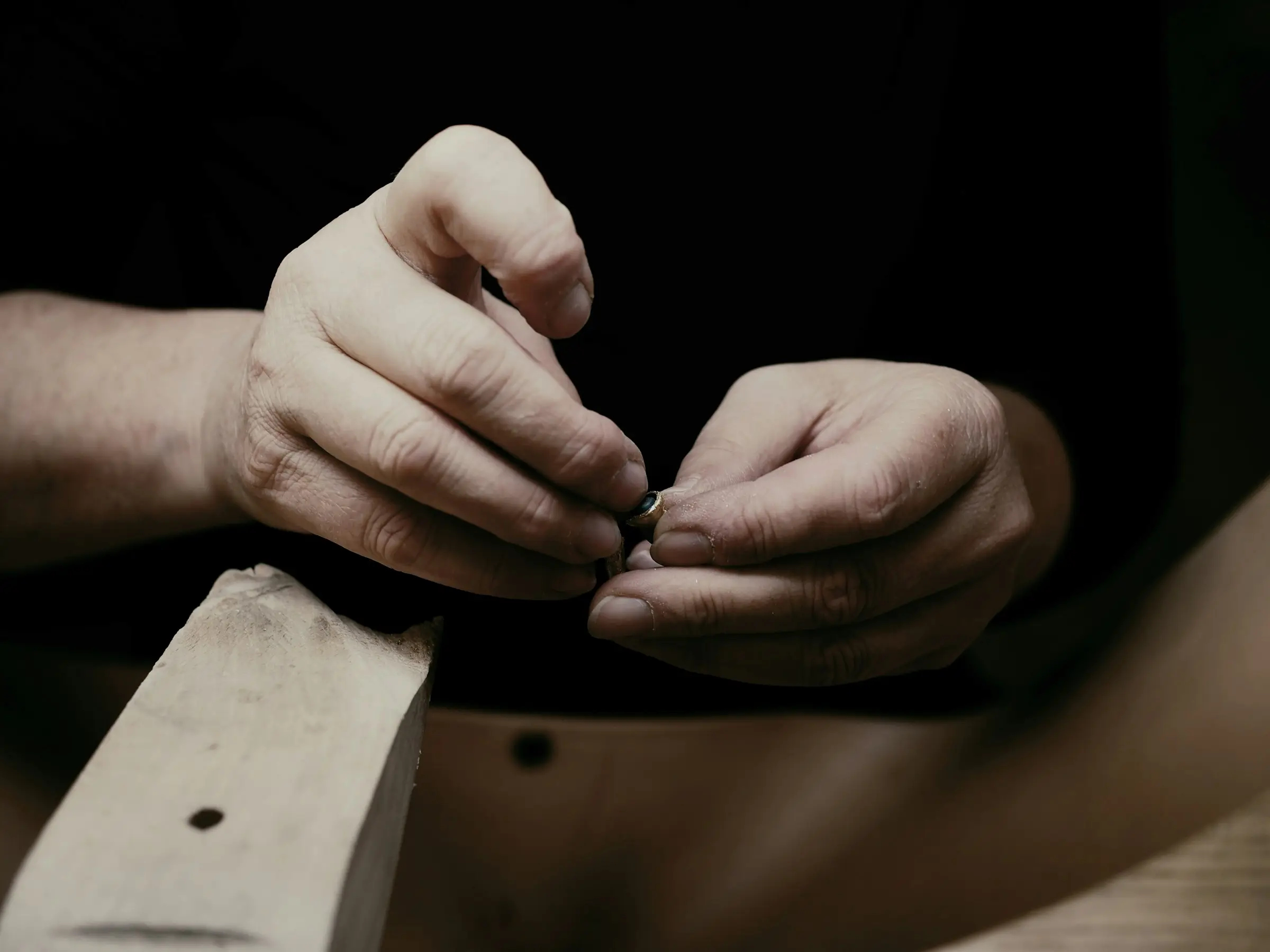 Le mani dell'orafo lavorano un piccolo gioiello appoggiate al banco
