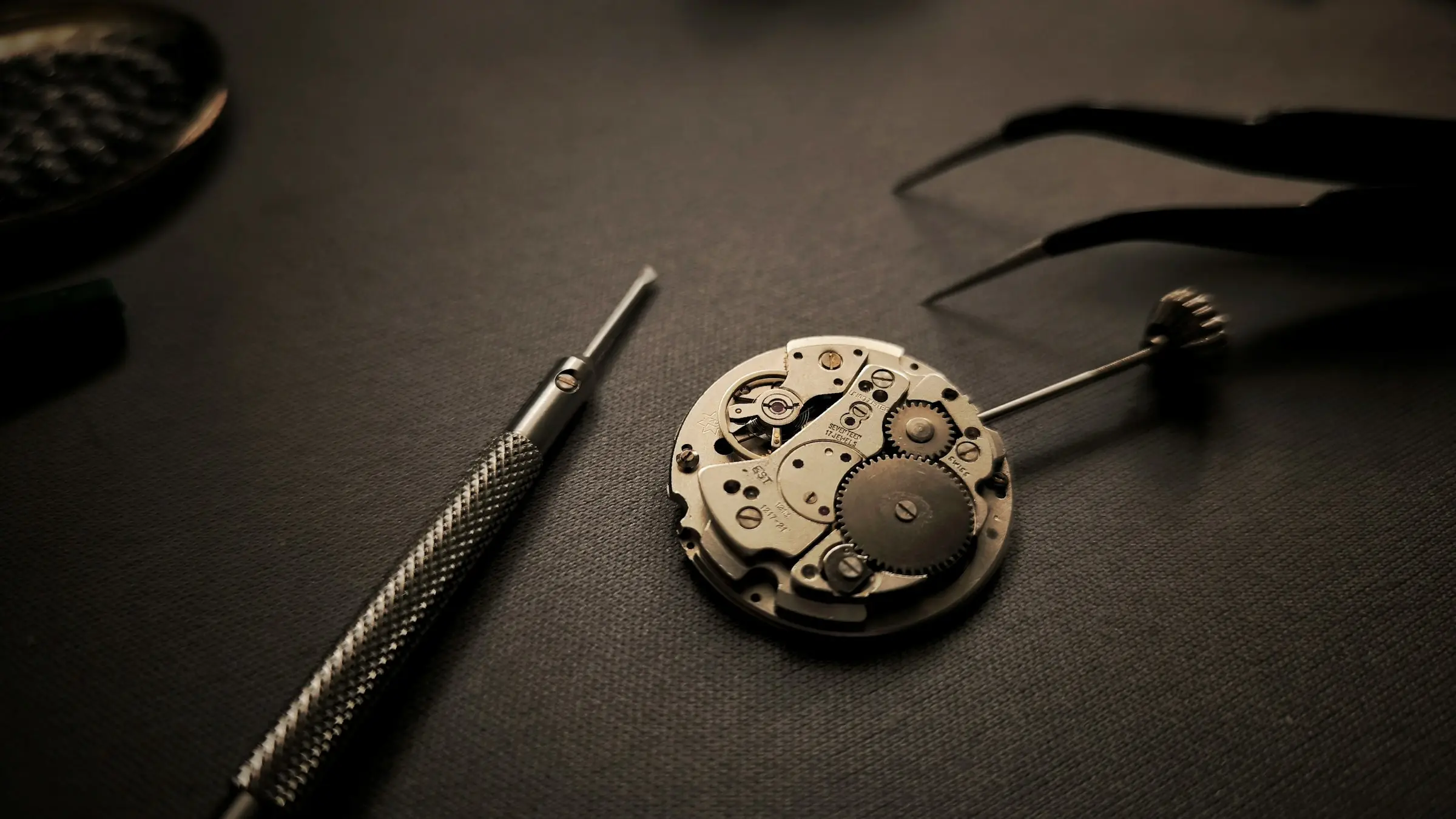 Un movimento meccanico di orologio aperto accanto ai cacciaviti
