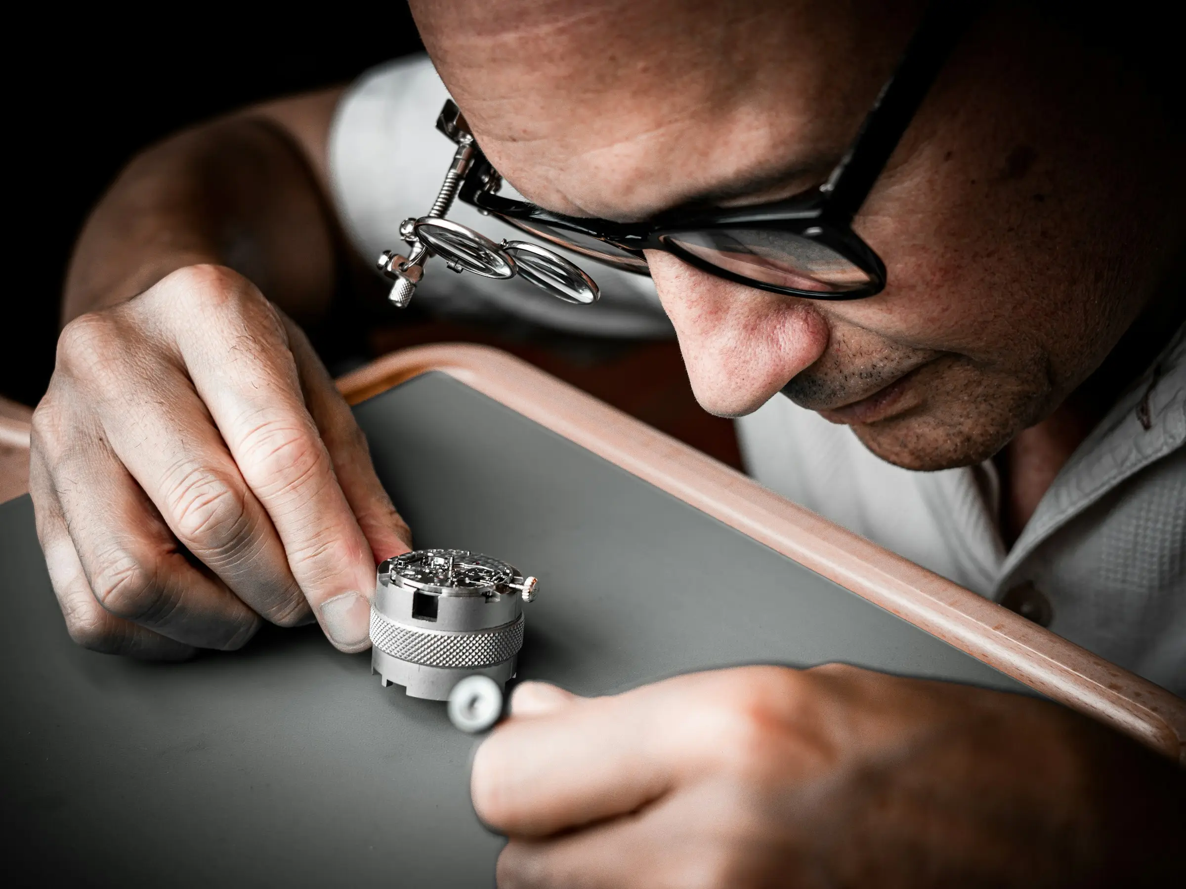 Un orologiaio con la lente lavora al movimento di un orologio